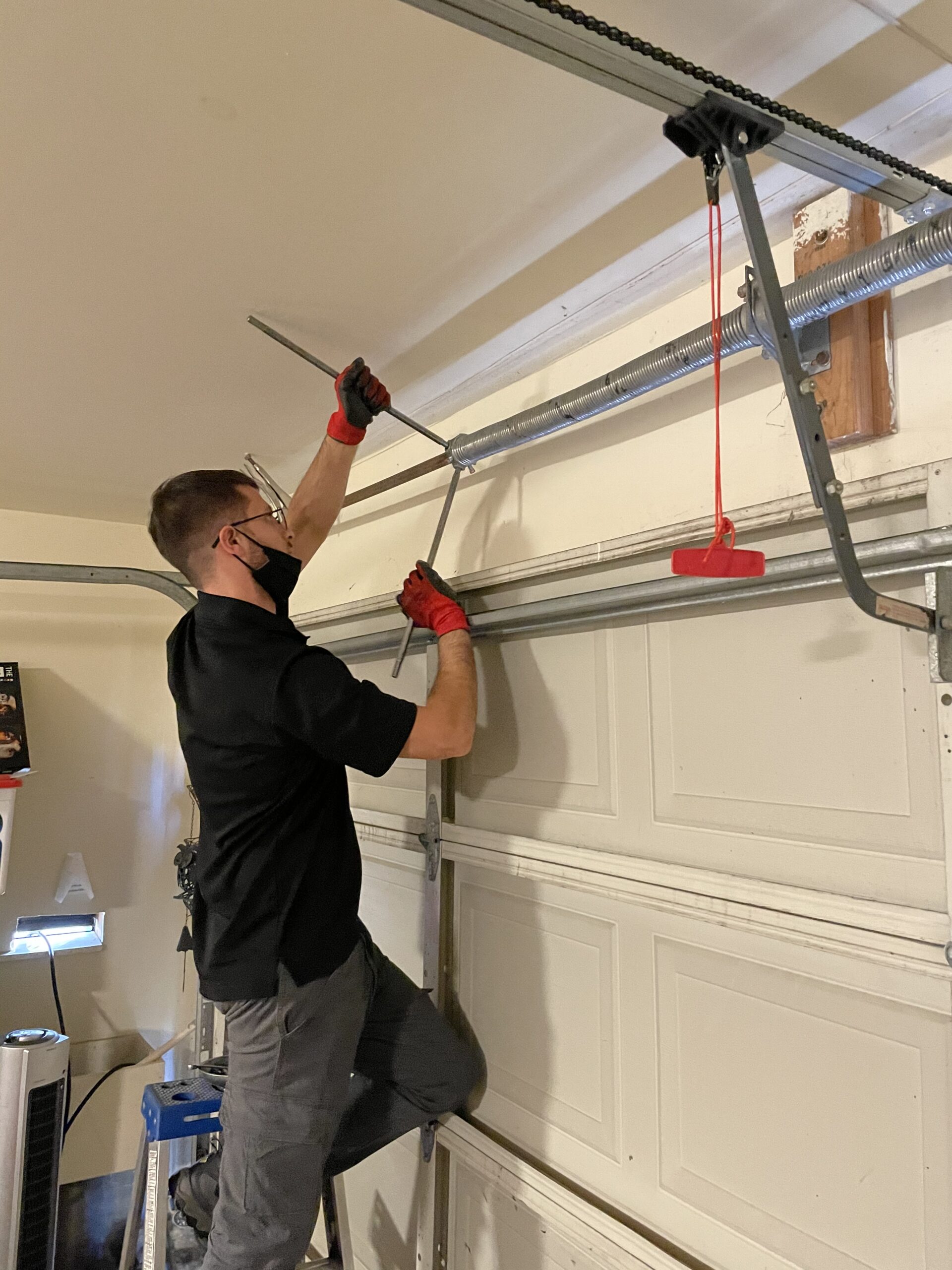 Man repairing garage door mechanism.